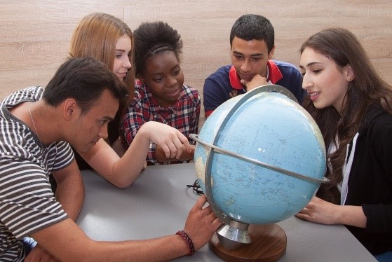 diverse group of young people looking at a desktop globe